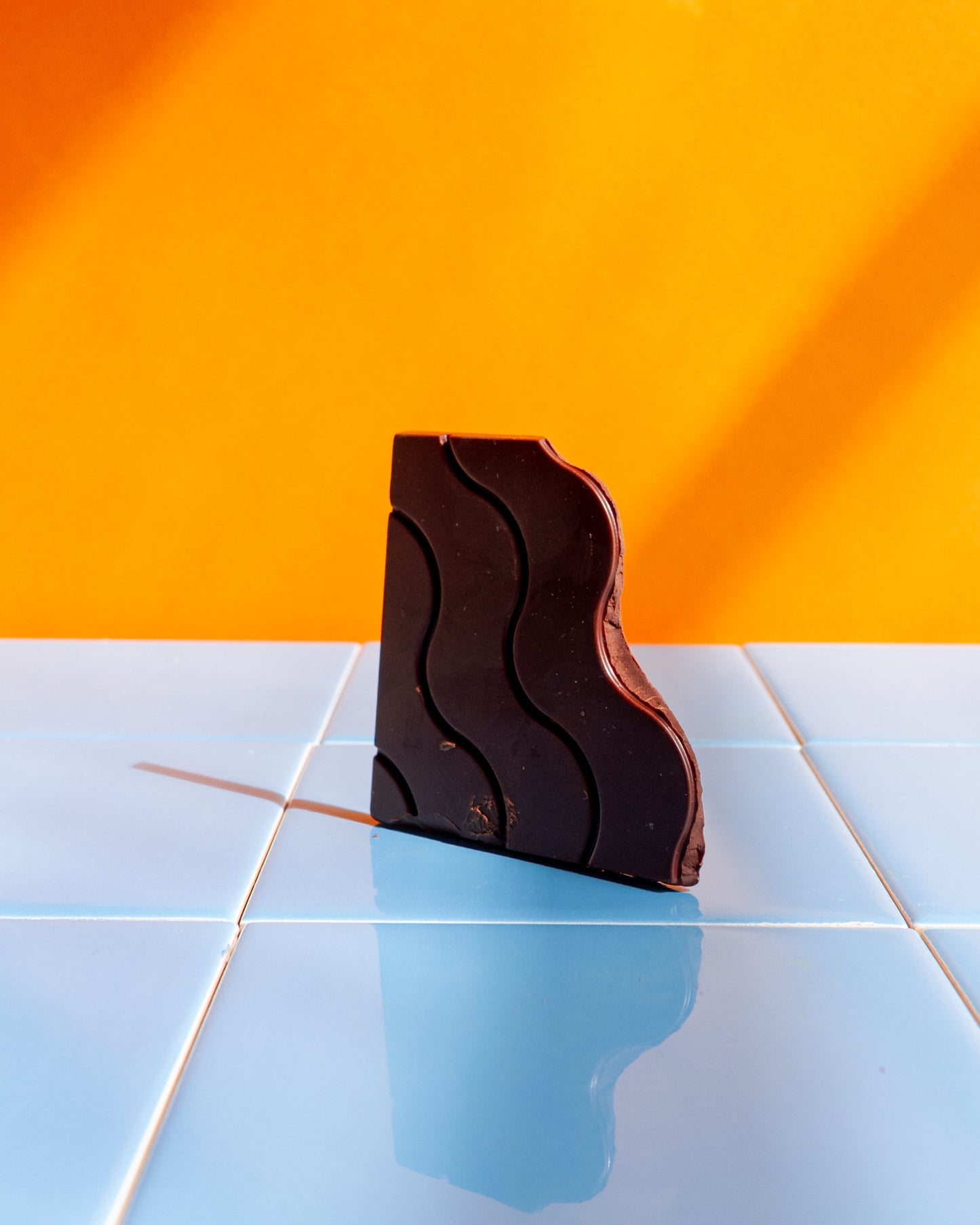 Tasty chocolate on yellow background, sky blue tile floor